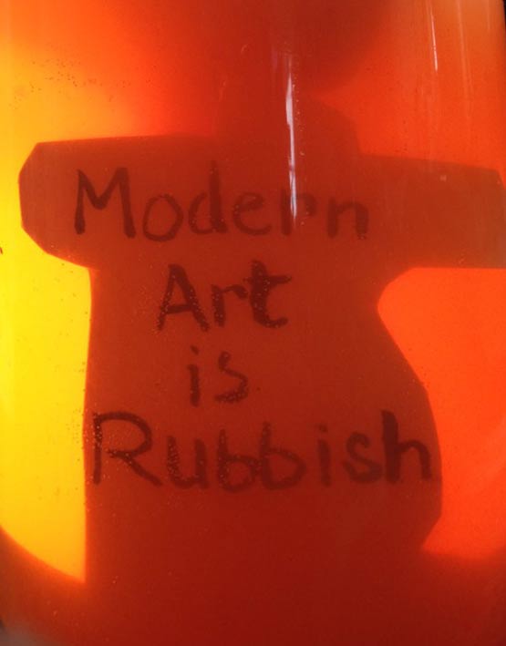 Modern art is rubbish written on card that looks like it is submerged in Orange Urine